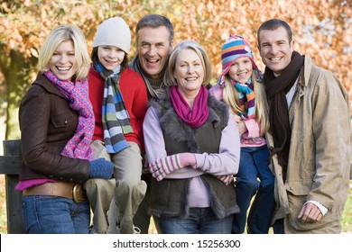 Multi-generation Family On Autumn Walk Sitting On Fence