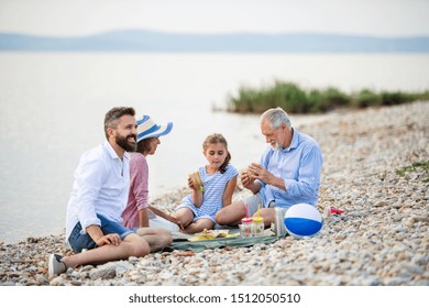 Multigeneration Family On A Holiday By The Lake, Having Picnic.