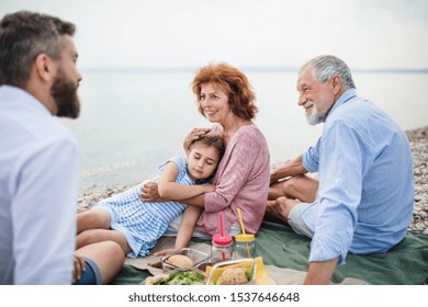 Multigeneration Family On A Holiday By The Lake, Having Picnic.