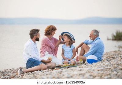 Multigeneration Family On A Holiday By The Lake, Having Picnic.