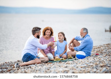 Multigeneration Family On A Holiday By The Lake, Having Picnic.