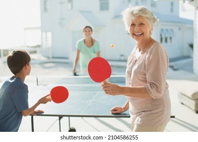 Multi-generation Family Playing Table Tennis Outside Beach House