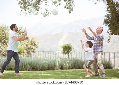 Multi-generation Family Playing Volleyball In Backyard