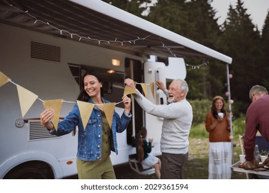 Multi-generation family preparing party by car outdoors in campsite, caravan holiday trip. - Shutterstock ID 2029361594