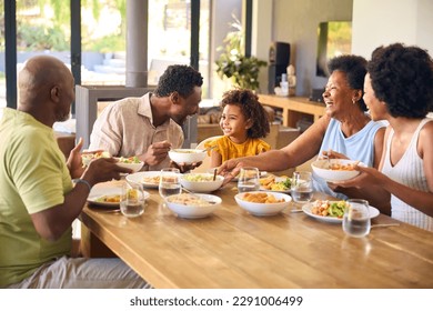 Multi-Generation Family Sitting Around Table Serving Food For Meal At Home - Powered by Shutterstock