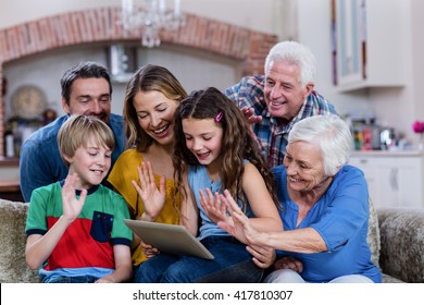 Multi-generation Family Waving Hands While Using Digital Tablet For Video Chat At Home