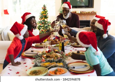 Multigeneration family wearing santa hats toasting while sitting and having lunch on dining table in the living room at home. christmas festivity tradition celebration concept - Powered by Shutterstock