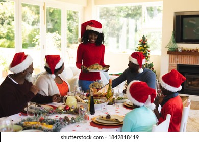 Multigeneration family  wearing santa hats having lunch together while sitting on dining table in the living room at home. christmas festivity tradition celebration concept - Powered by Shutterstock