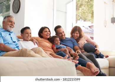 Multi-Generation Hispanic Family Relaxing At Home Sitting On Sofa Watching TV Together