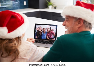 Multi-Generation Hispanic Family Wearing Santa Hats With Laptop Having Video Chat At Christmas - Powered by Shutterstock