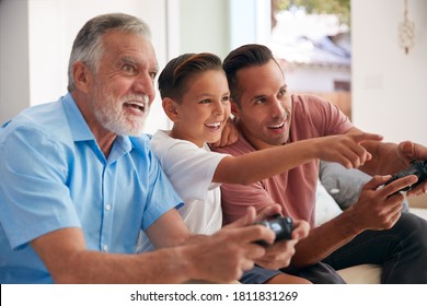 Multi-Generation Male Hispanic Family Playing Video Game At Home Sitting On Sofa Together