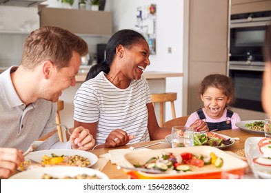 Multi-Generation Mixed Race Family Eating Meal Around Table At Home Together