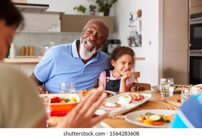 Multi-Generation Mixed Race Family Eating Meal Around Table At Home Together