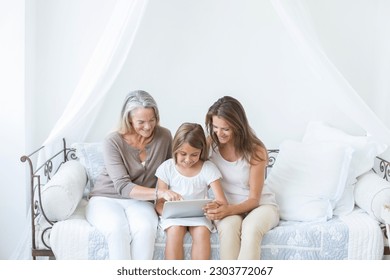 Multi-generation women using digital tablet on daybed - Powered by Shutterstock