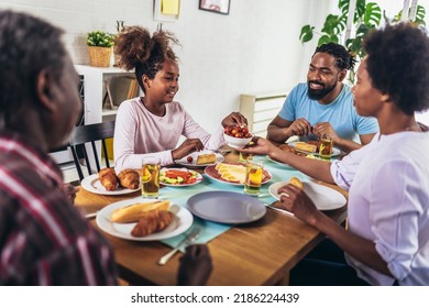 A Multi-generational African-American Family Enjoying Food At Their Dinner Table.