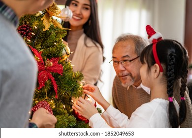 Multigenerational asian Family decorating a Christmas tree. Mom Dad daughter girl and grandfather decorate the Christmas tree prepare for season greeting of Merry Christmas and Happy Holidays. - Powered by Shutterstock