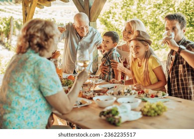 Multigenerational family enjoying a lunch on the balcony of a house in a vineyard in the countryside - Powered by Shutterstock