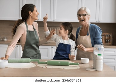 Multigenerational family, grandma, daughter and grandkid having fun while cooking together in kitchen, wearing aprons, joyfully baking, preparing food, exude love, creating memories across generations - Powered by Shutterstock