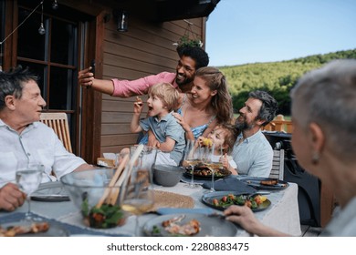 Multigenerational family having bbq party and taking selfie. - Powered by Shutterstock