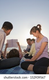 Multigenerational Family Relaxing And Reading On The Beach