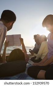 Multigenerational Family Relaxing And Reading On The Beach