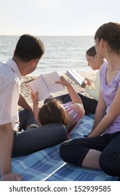 Multigenerational Family Relaxing And Reading On The Beach