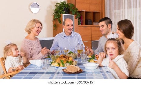 Multigenerational Family Sitting At The Table Set For Dinner At Home