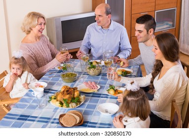 Multigenerational Family Sitting And Talking At The Table Set For Dinner