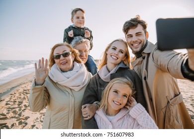 multigenerational family taking selfie on smartphone at seaside - Powered by Shutterstock