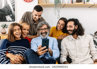 Multi-generational family using mobile phone sitting together on sofa at home. Technology and domestic lifestyle concept. - Powered by Shutterstock