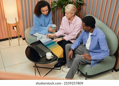 Multigenerational group of interior designers choosing upholstery fabric on color samples while working collaboratively in lounge area on comfy seats in modern coworking center - Powered by Shutterstock