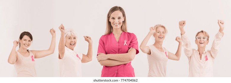 Multigenerational Group Of Women With Their Hands Up And Female Oncologist Standing In The Middle