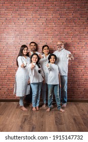 Multigenerational Indian Asian Family Showing Or Holding Glasses Full Of Milk Against Brick Wall