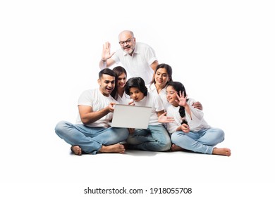 Multigenerational Indian Asian Family Of Six Online Shopping Using Laptop And Electronic Card While Sitting Against White Background