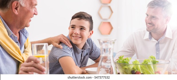 Multigenerational Men In Family Eating Dinner At Home Together