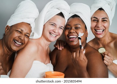Multigenerational women having fun applying face beauty masks on their face - Main focus on caucasian woman face