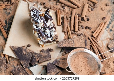 a multi-layered cake made of chocolate and cream cakes in a chaotic order in the cake, there is a lot of chocolate, cinnamon and cocoa powder scattered around the cake - Shutterstock ID 2103717299