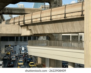 A multilayered urban scene with elevated rail tracks above busy city traffic, showcasing modern infrastructure, dense development, and daily metropolitan transit.