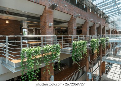 Multi-level atrium featuring brickwork, plants, and natural light, creating an open and inviting indoor environment.