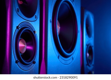 Multimedia acoustic sound speakers with neon lighting. Sound audio system with two satellites and subwoofer on dark background.