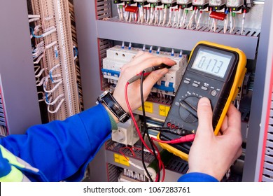 multimeter is in hands of engineer in electrical cabinet. Adjustment of automated control system for industrial equipment control cabinets. electrician measures voltage by tester