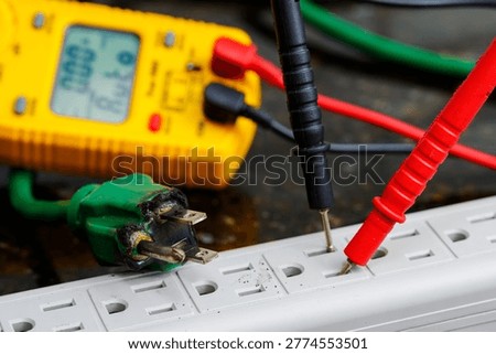 Multimeter testing damaged electrical cord for voltage, safety inspection, repair diagnosis, and fire hazard prevention.