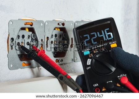 Multimeter (voltmeter) measuring voltage in a wall socket — practical demonstration of electrical testing, safety, and home diagnostics.