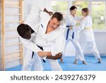 Multinational athletes in white kimonos practice Brazilian jiu Jitsu Aikido Wing chun wrestling. Training at Academy of Martial Arts martial arts hand-to-hand combat.