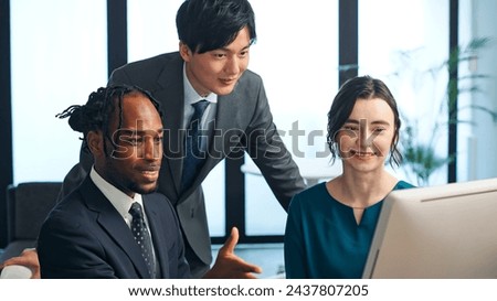 Multinational businesspeople talking while looking at PC monitor in the lobby. International business.