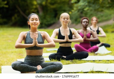 Multinational Girls Doing Breathing Exercises Or Meditation During Outdoor Yoga Class, Empty Space