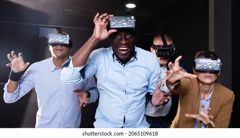 Multinational group of colleagues using VR glasses during team building seminar