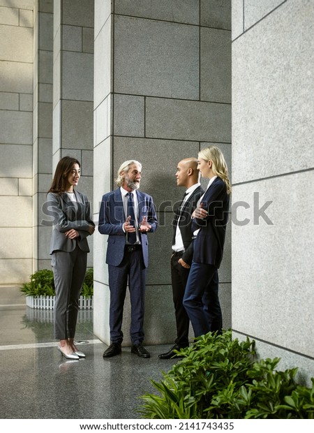 multinational and multiethnic\
business people standing talking chatting in lobby of modern office\
building