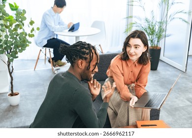 Multinational people talking while looking at laptops in the lobby