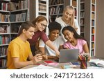 Multinational Team Of College Students Talking Over Project, girl pointing at laptop screen, library interior